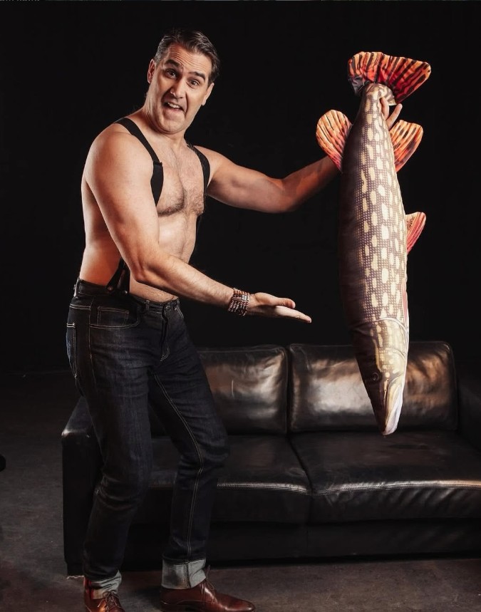 Andreas Barås barbröstad med en stor fiskattrapp framför en soffa.